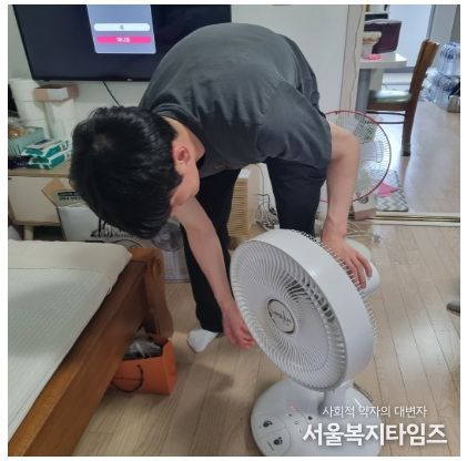 성동구의 동 주민센터 직원이 어르신 댁에 선풍기를 조립해주고 있다.