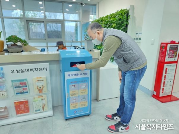 주민이 폐의약품 전용수거함에 사용하지 않는 의약품을 버리고 있다. 