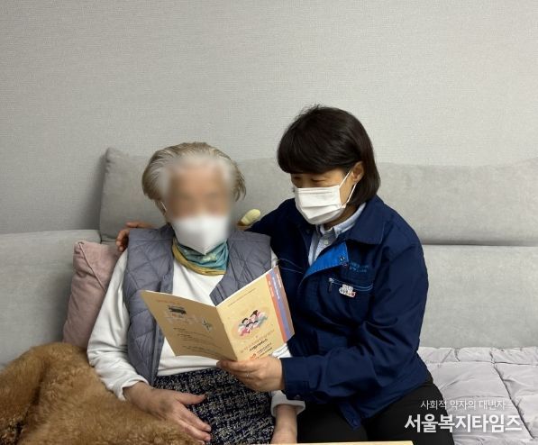 기억배지를 착용한 도시가스 검침원이 어르신의 안부를 살피며 동작구 치매안심센터 지원 서비스를 안내하고 있는 모습