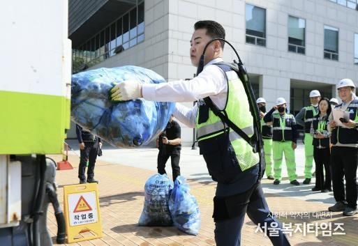 오언석 도봉구청장이 ‘입는 로봇’을 입고 쓰레기를 청소차에 옮기고 있다