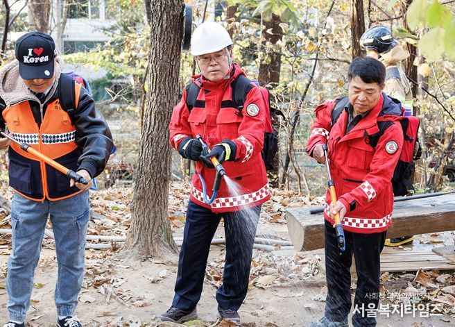 진교훈 서울 강서구청장(가운데)이 21일 오후 우장산 일대에서 열린 ‘유관기관 합동 산불진압훈련’에서 등짐펌프를 매고 산불진화대원과 함께 잔불진화작업을 하고 있다.