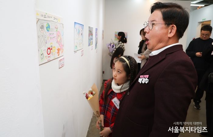 박강수 마포구청장이 수상 어린이와 함께 전시된 그림을 살펴보고 있다.