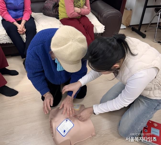 구 관계자가 경로당 어르신에게 자동심장충격기 사용법을 안내하고 있다.